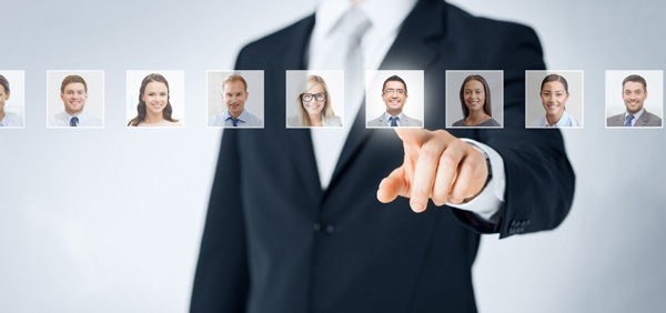 Photo of a male torso dressed in a business suit and pointing to (selecting) from a line up of small headshots representing potential employees